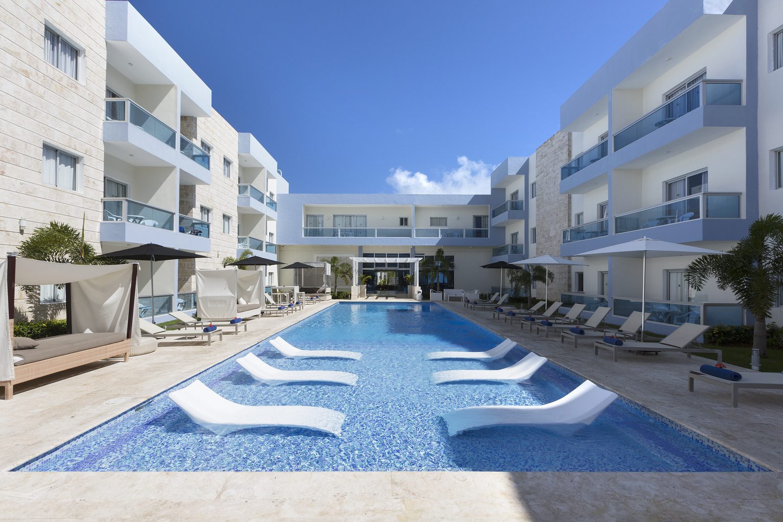 Piscina central con camas balinesas rodeada por el hotel